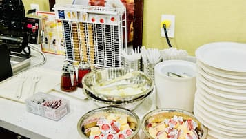Montaje de buffet con diferentes opciones de comida, incluyendo tazones de queso y una presentación de waffles.