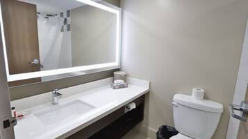 Un baño moderno con un espejo grande, un lavabo y un inodoro.