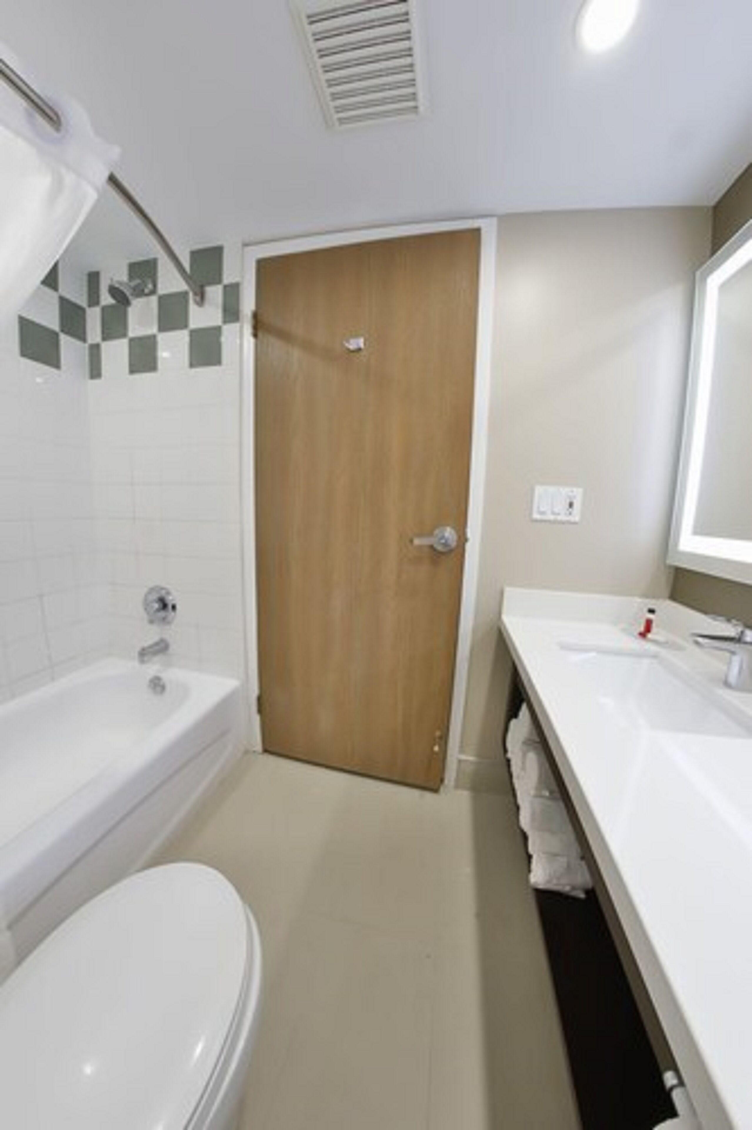 A modern bathroom with a bathtub, toilet, and a vanity with a mirror.