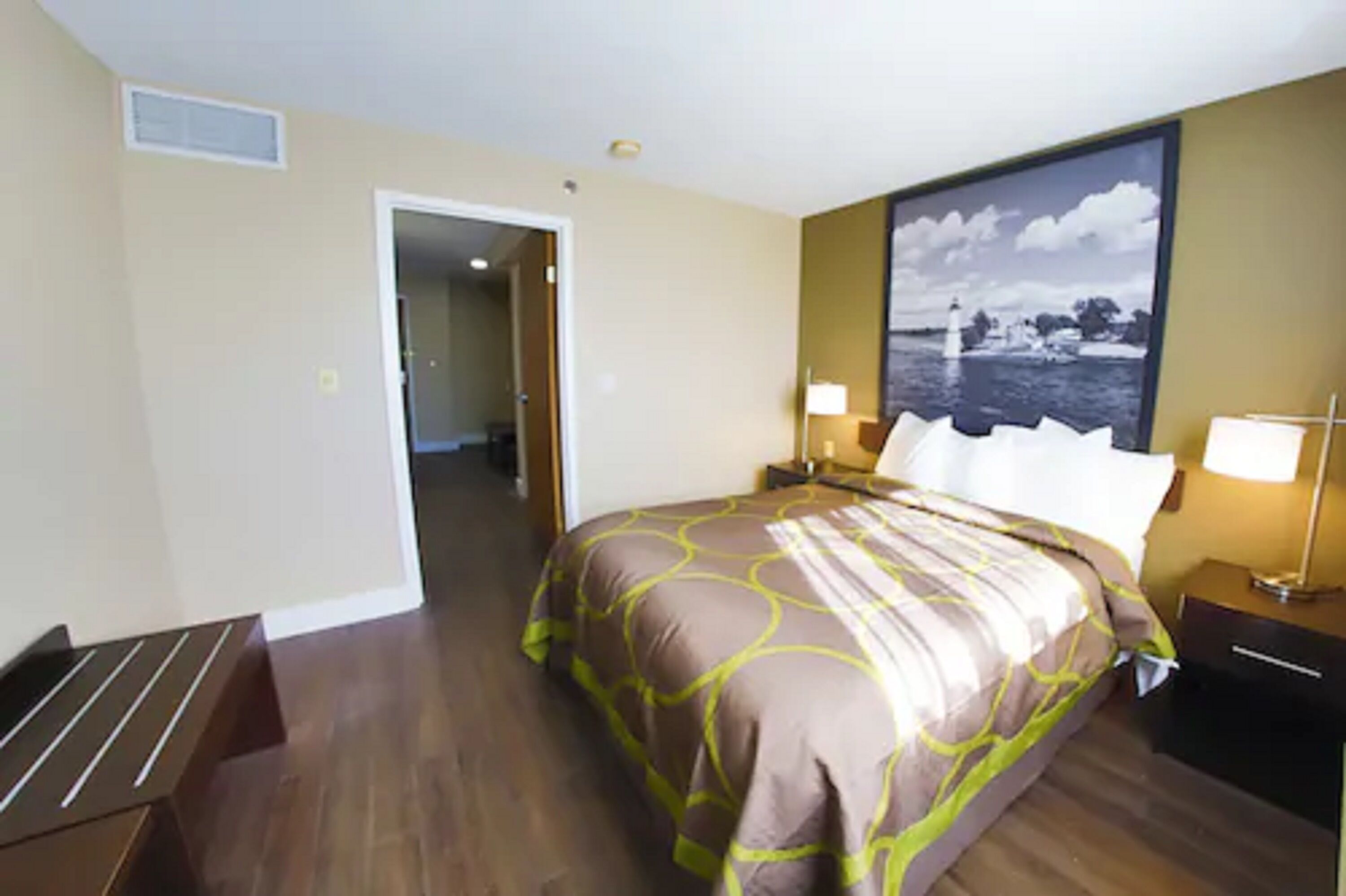 Habitación de hotel con una cama grande, dos mesitas de noche, un banco y un cuadro en la pared.