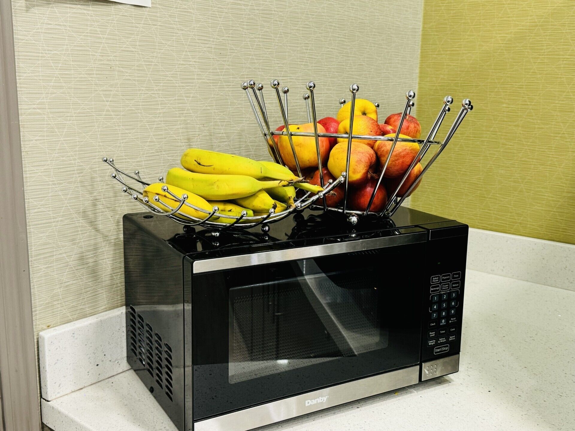 Um micro-ondas com uma cesta de frutas em cima.