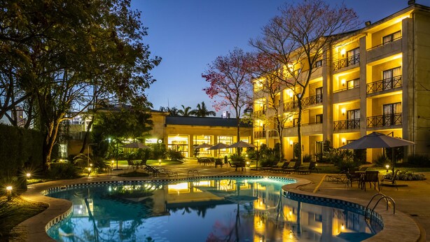 Un hôtel doté d’une piscine, d’un espace extérieur aménagé et d’une cour bien éclairée au crépuscule.