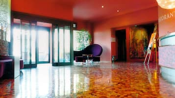 A spacious lobby with a polished floor, a reception desk, and a seating area with a purple chair.
