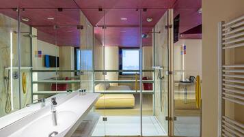 A modern bathroom with a large mirror, a white sink, and a glass shower enclosure.