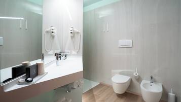 Un baño moderno con un espejo grande, un lavabo, un inodoro y un bidé.