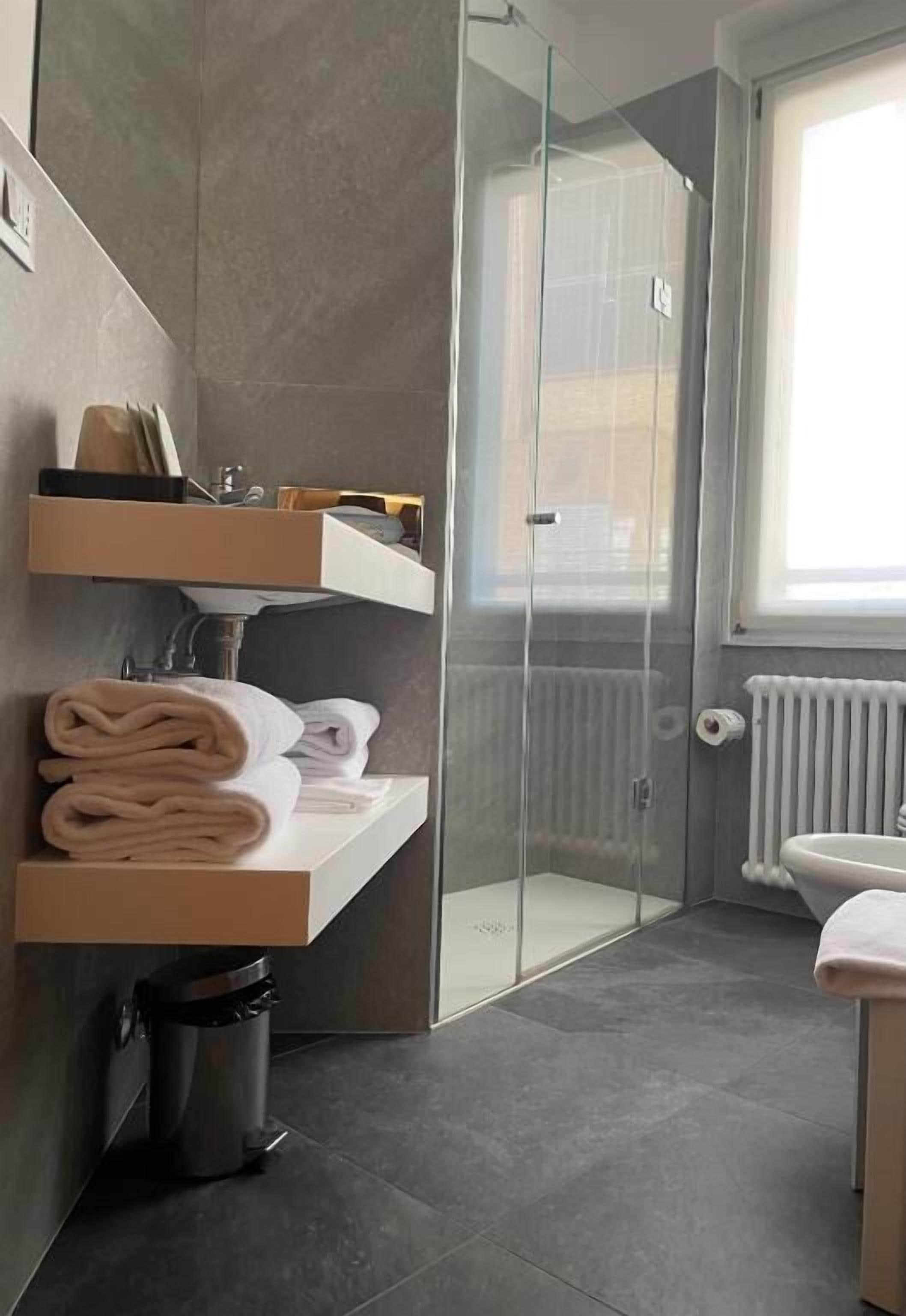 Un baño moderno con cabina de ducha de vidrio, lavamanos y ventana que proporciona luz natural.