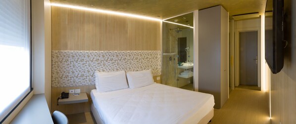 A hotel room with a bed, bedside table, and a bathroom with a shower and sink. - Hotel Là di Moret (Udine)