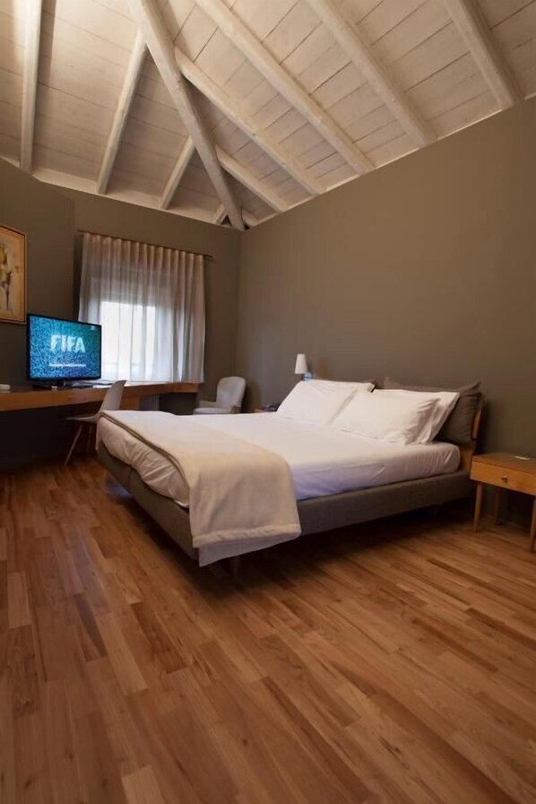 A bedroom with a bed, a desk, a chair, a TV, and a window with curtains. - Hotel Là di Moret (Udine)