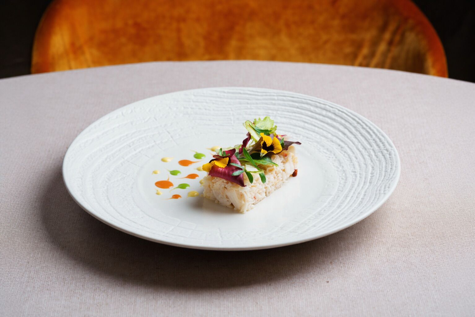 Un plato blanco con un bocado de comida sobre un mantel texturizado.