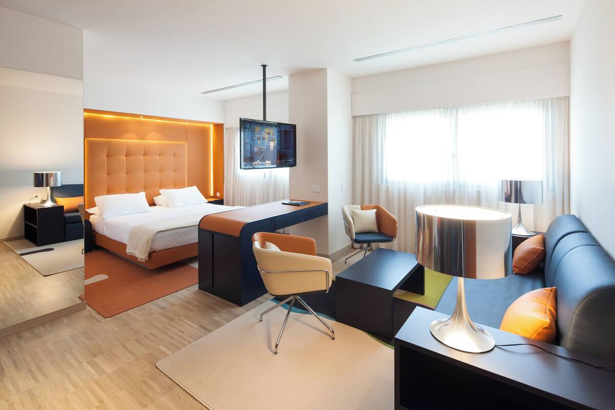 Une chambre d’hôtel moderne équipée d’un grand lit, d’un bureau, d’un canapé et d’une télévision.