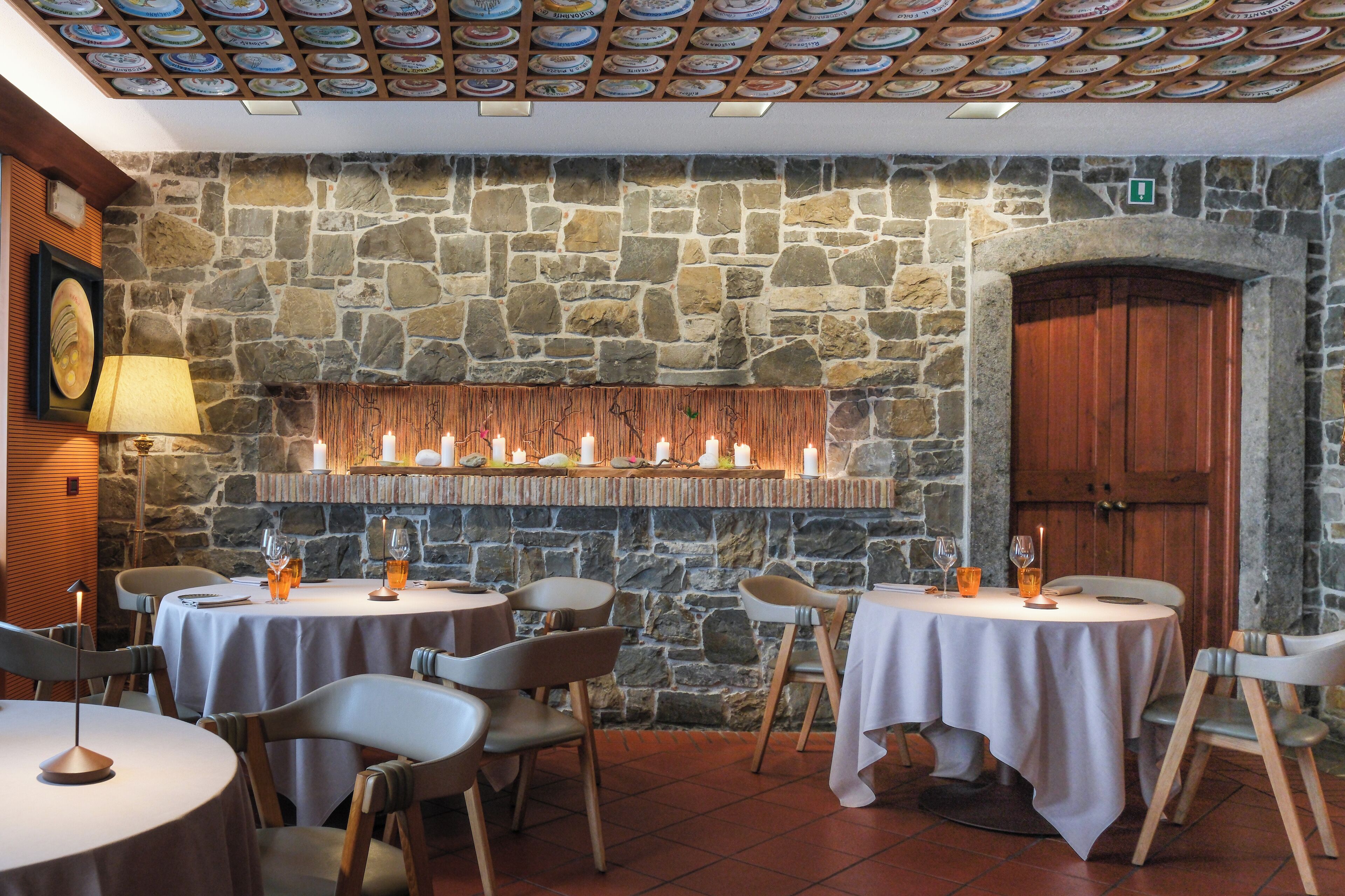 A restaurant with stone walls, round tables, and chairs.