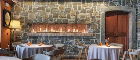 Un restaurante con paredes de piedra, mesas redondas y sillas.