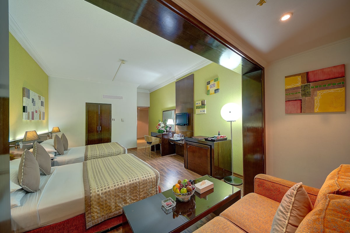 Habitación de hotel con dos camas, un sofá, un escritorio y una televisión.