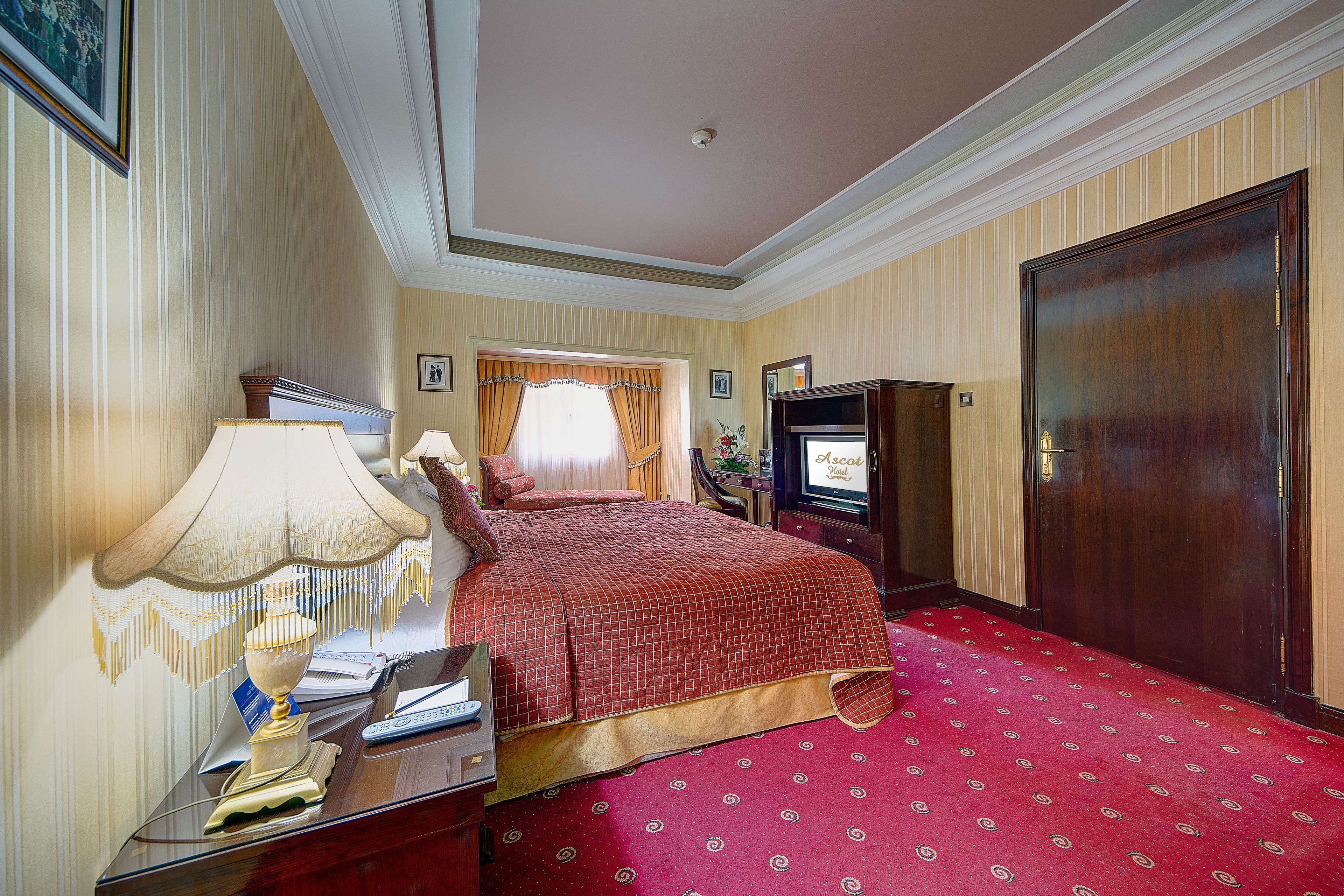 Una habitación de hotel con una cama grande, un escritorio con lámpara, televisión y armario.