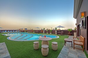 Una piscina al aire libre, sombrillas, sillones reclinables de piscina
