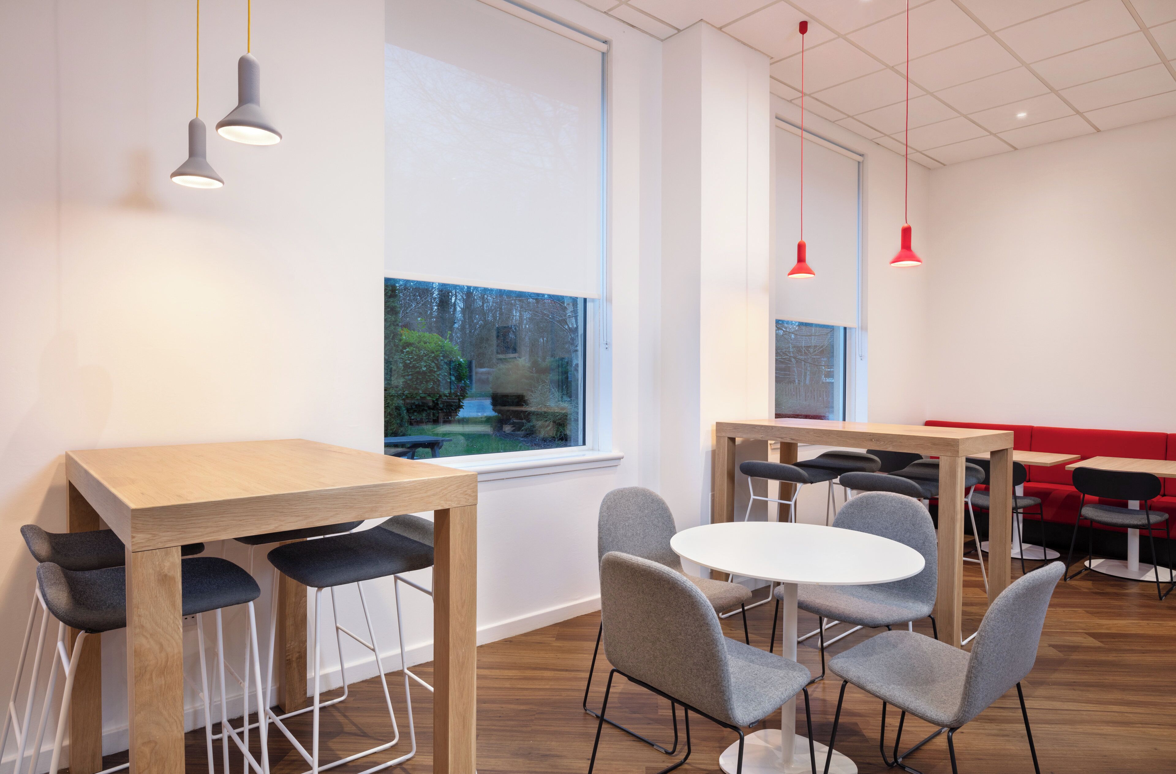 Un interior moderno con una mesa y sillas de madera, un sofá rojo e iluminación colgante.