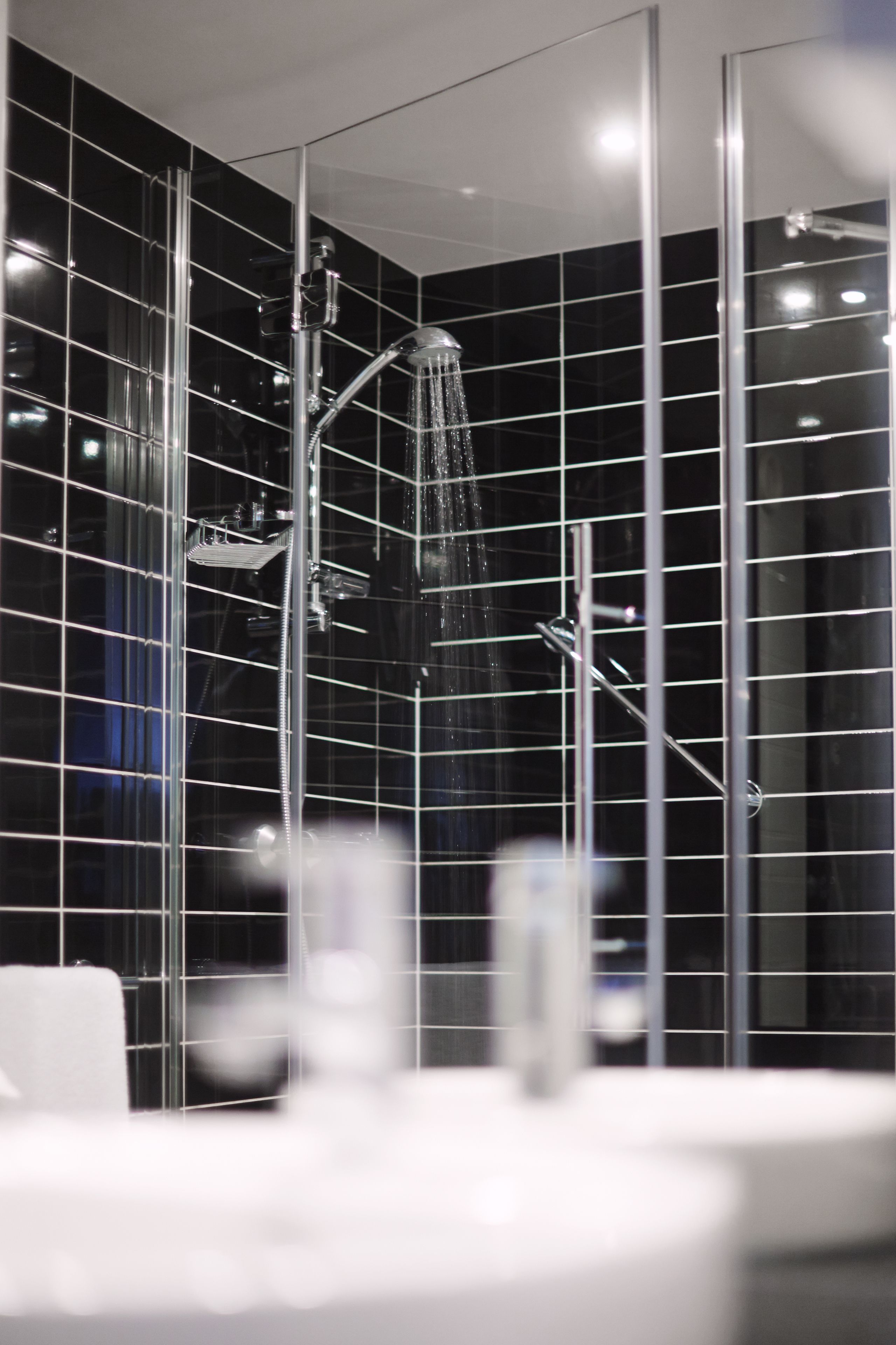 A modern bathroom with a glass-enclosed shower, chrome fixtures, and a tiled wall.