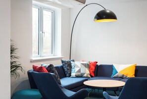 Un soggiorno moderno con un divano blu, un tavolino rotondo in legno e una lampada da terra nera.