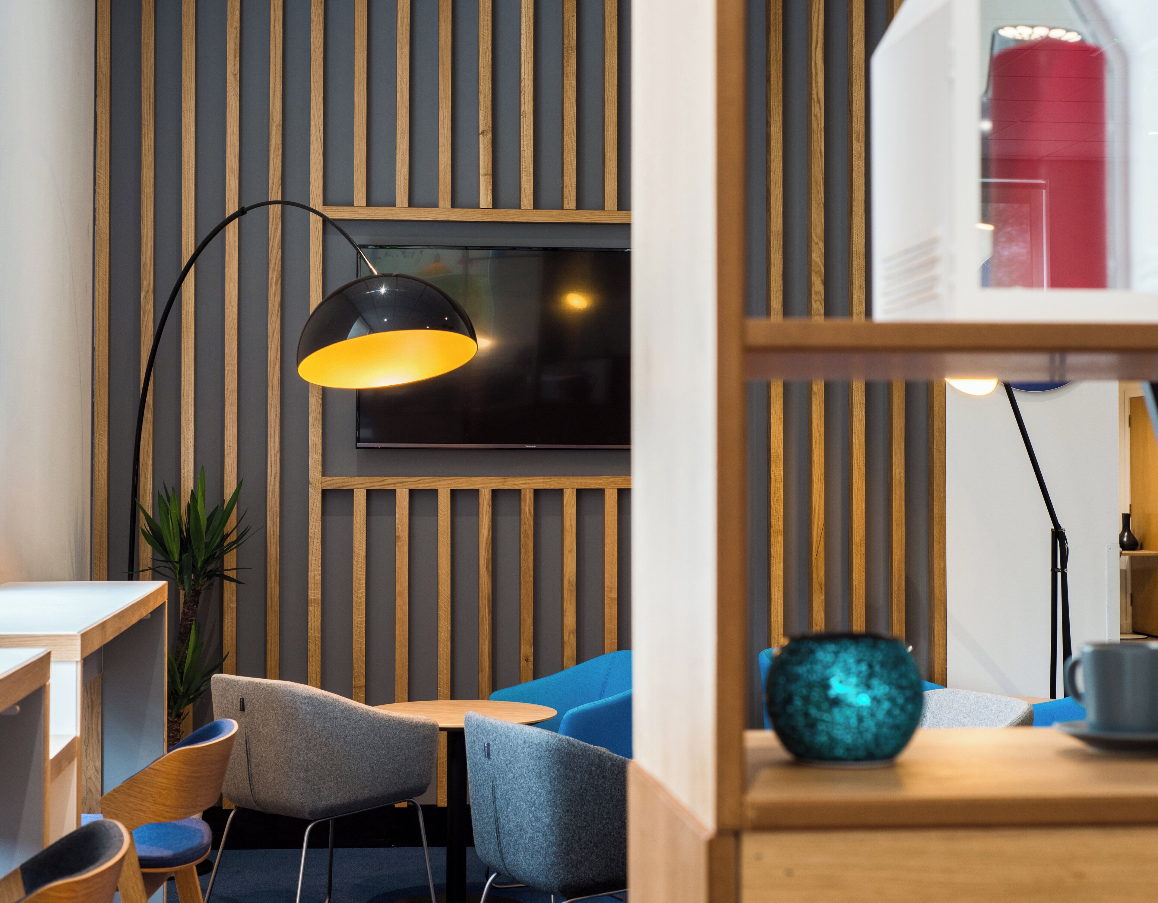 Un interior moderno con un panel de madera, un televisor de pantalla plana y un sofá azul.