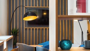 A modern interior with a wooden slat wall, a flat-screen TV, and a blue sofa. - Holiday Inn Express Strathclyde Park M74 JCT 5 by IHG (Glasgow)