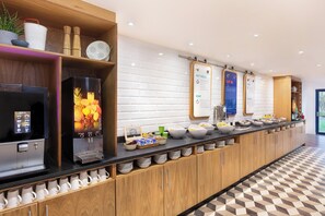 A modern kitchen with a long counter, a fruit dispenser, and a coffee machine. - Holiday Inn Express Strathclyde Park M74 JCT 5 by IHG (Glasgow)
