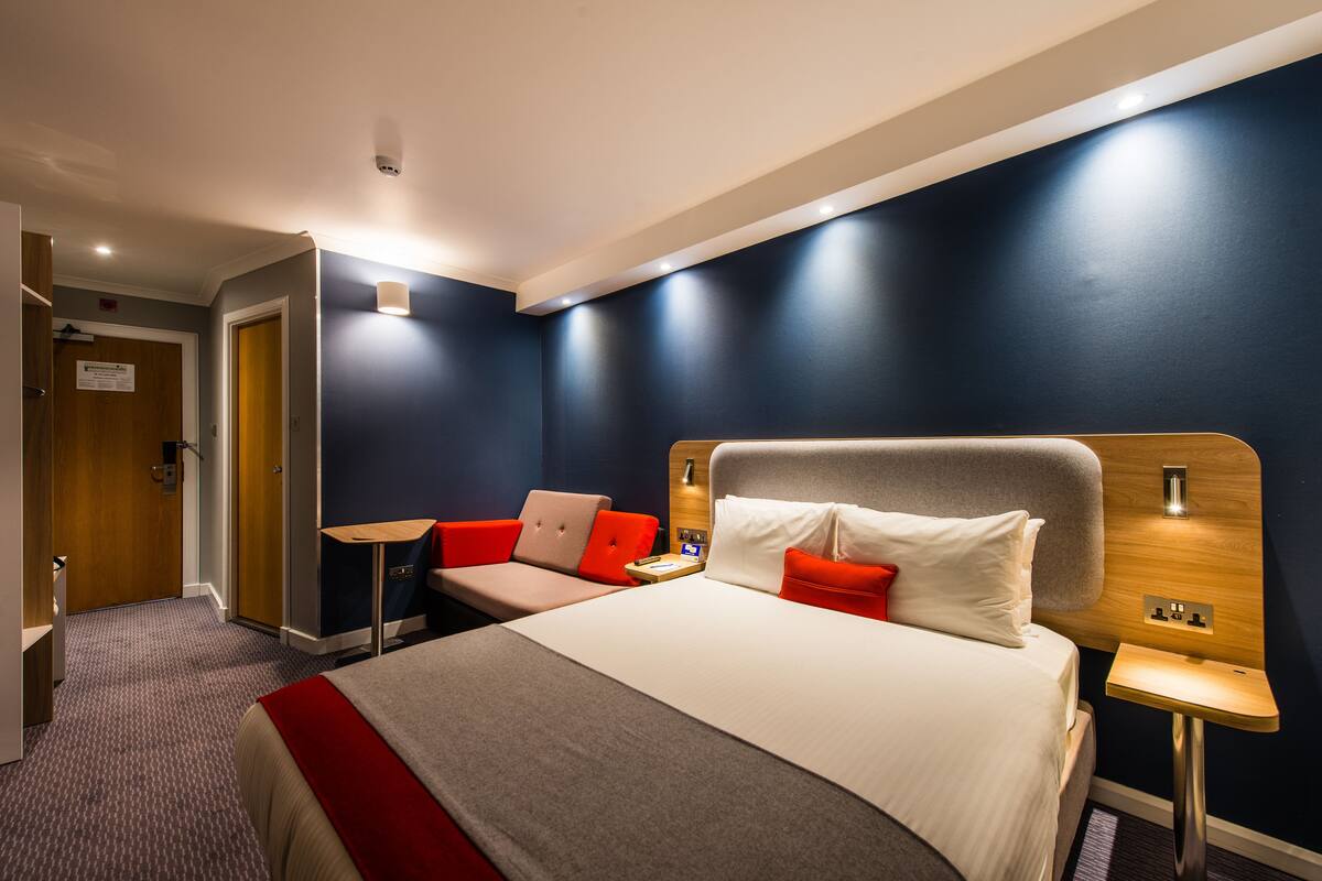 A hotel room with a bed, a desk, and a chair.
