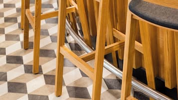 Een bar met houten barkrukken en een geruit vloerpatroon.
