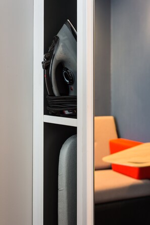 Une pièce moderne avec un mur blanc, un canapé gris et un pouf rouge et blanc.