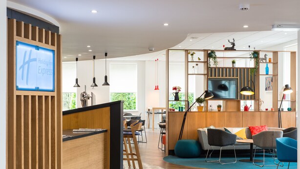 A modern hotel lobby with a reception desk, seating area, and a large window offering a view of greenery. - Holiday Inn Express Strathclyde Park M74 JCT 5 by IHG (Glasgow)