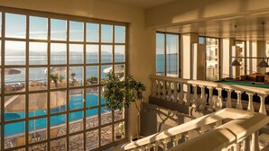 A room with a view of a pool and the sea, a balcony with a pool table, and a dining area with umbrellas. - Canvas by Mitsis Belvedere (Corfu)
