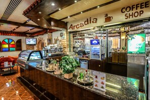 A coffee shop interior with a counter, seating area, and various coffee-making equipment. - BM Beach Hotel (Ras Al Khaimah)