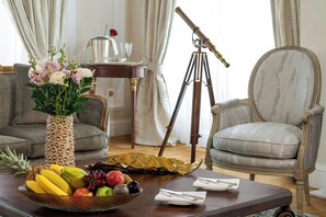 A room with a dining table set for two, a vintage telescope, a vase with flowers, and a fruit bowl.