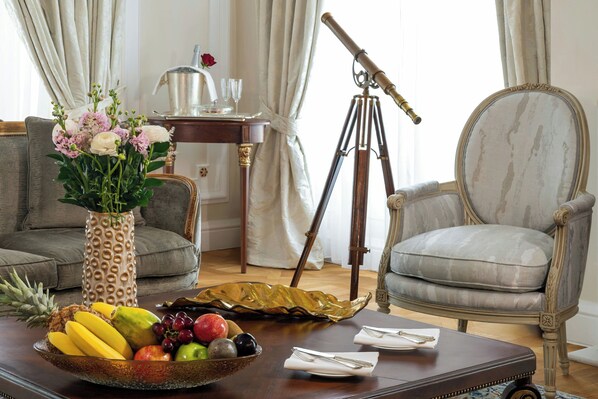 A room with a dining table set for two, a vintage telescope, a vase with flowers, and a fruit bowl.