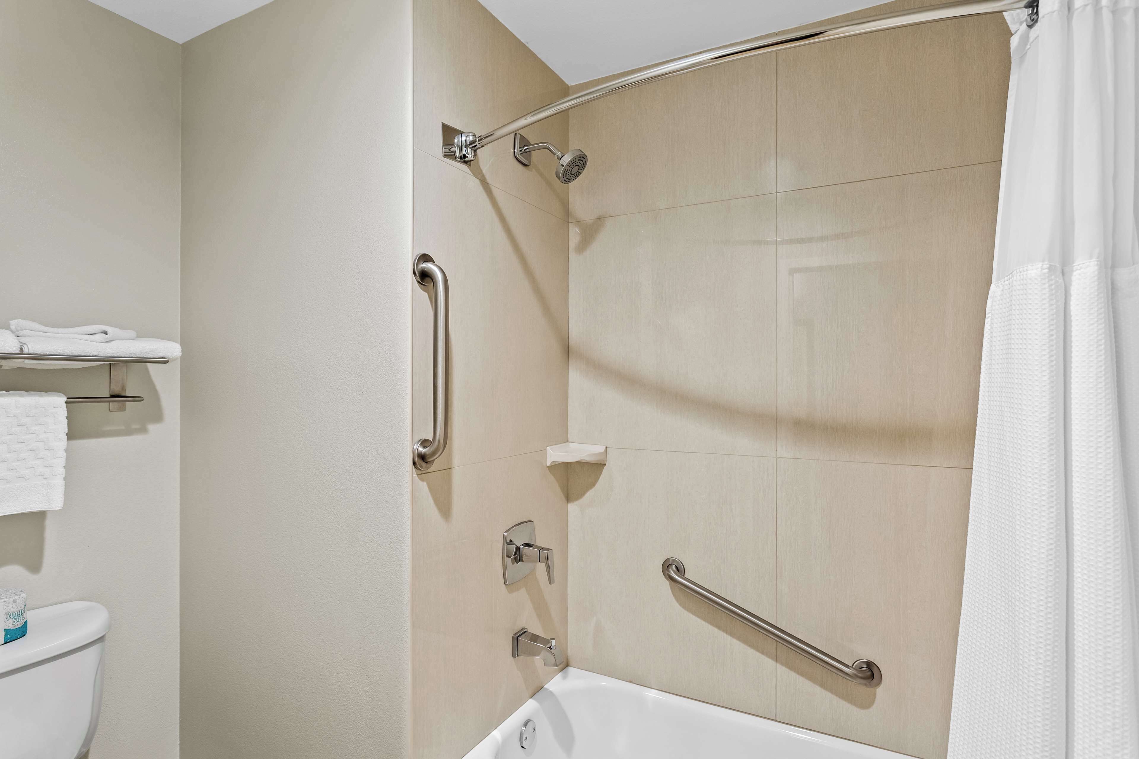 Un bagno moderno con doccia, toilette e mancorrenti.