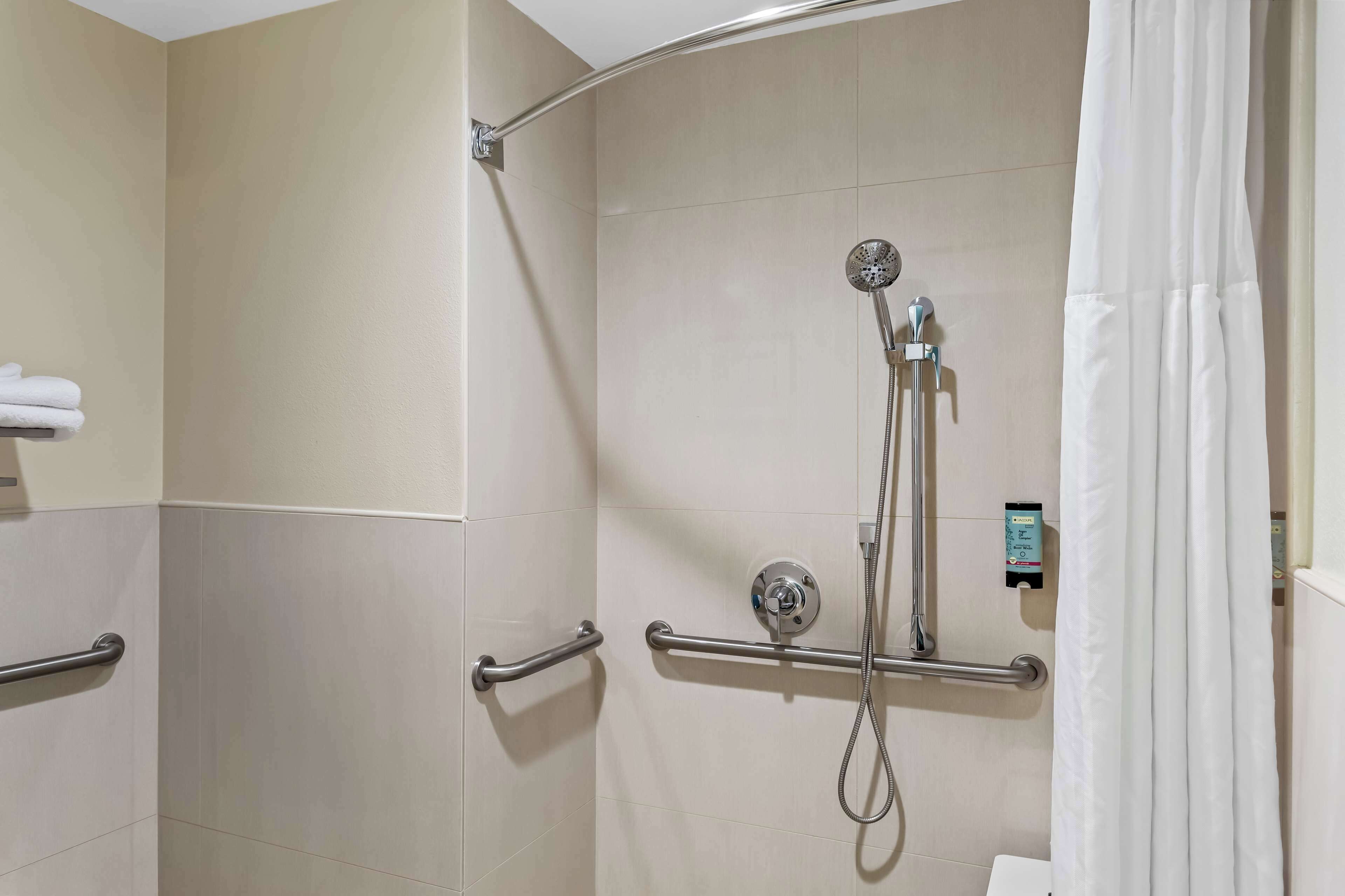 A shower area with a handheld showerhead, a wall-mounted faucet, and a control panel.