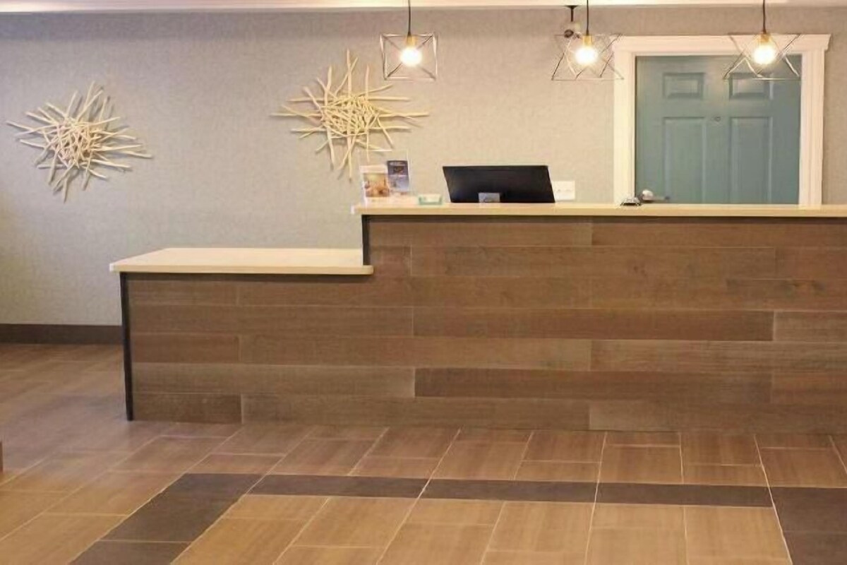 A reception desk with a wooden counter, two wall-mounted light fixtures, and a door in the background.