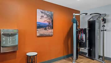 A gym with a pull-up bar, a water dispenser, and a painting of a landscape.