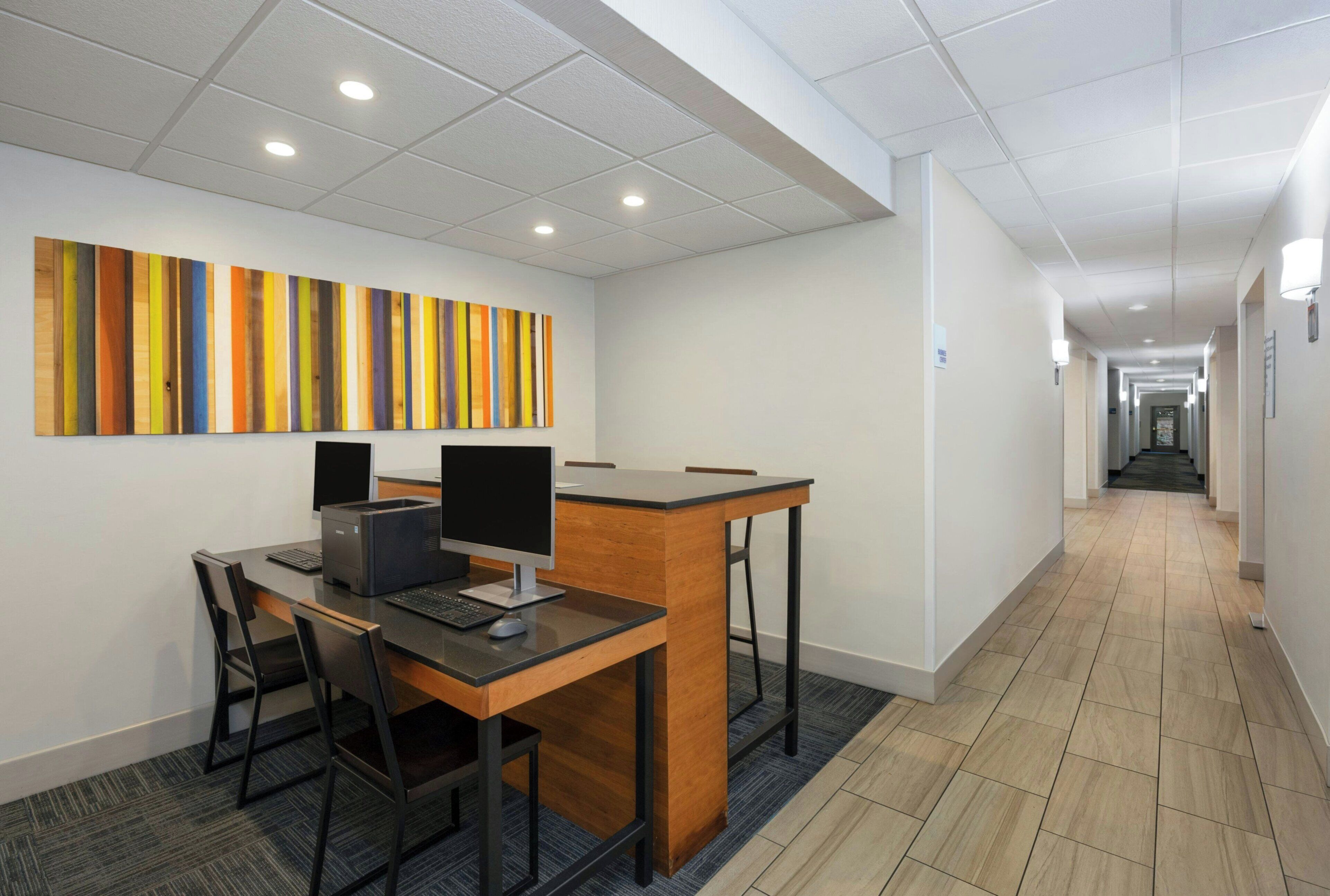 A modern office space with a desk, computer, and chairs.