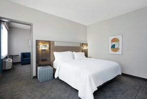 A hotel room with a bed, bedside tables, a chair, a small table, and a wall-mounted artwork. - Holiday Inn Express & Suites Acworth - Kennesaw Northwest by IHG (Acworth)
