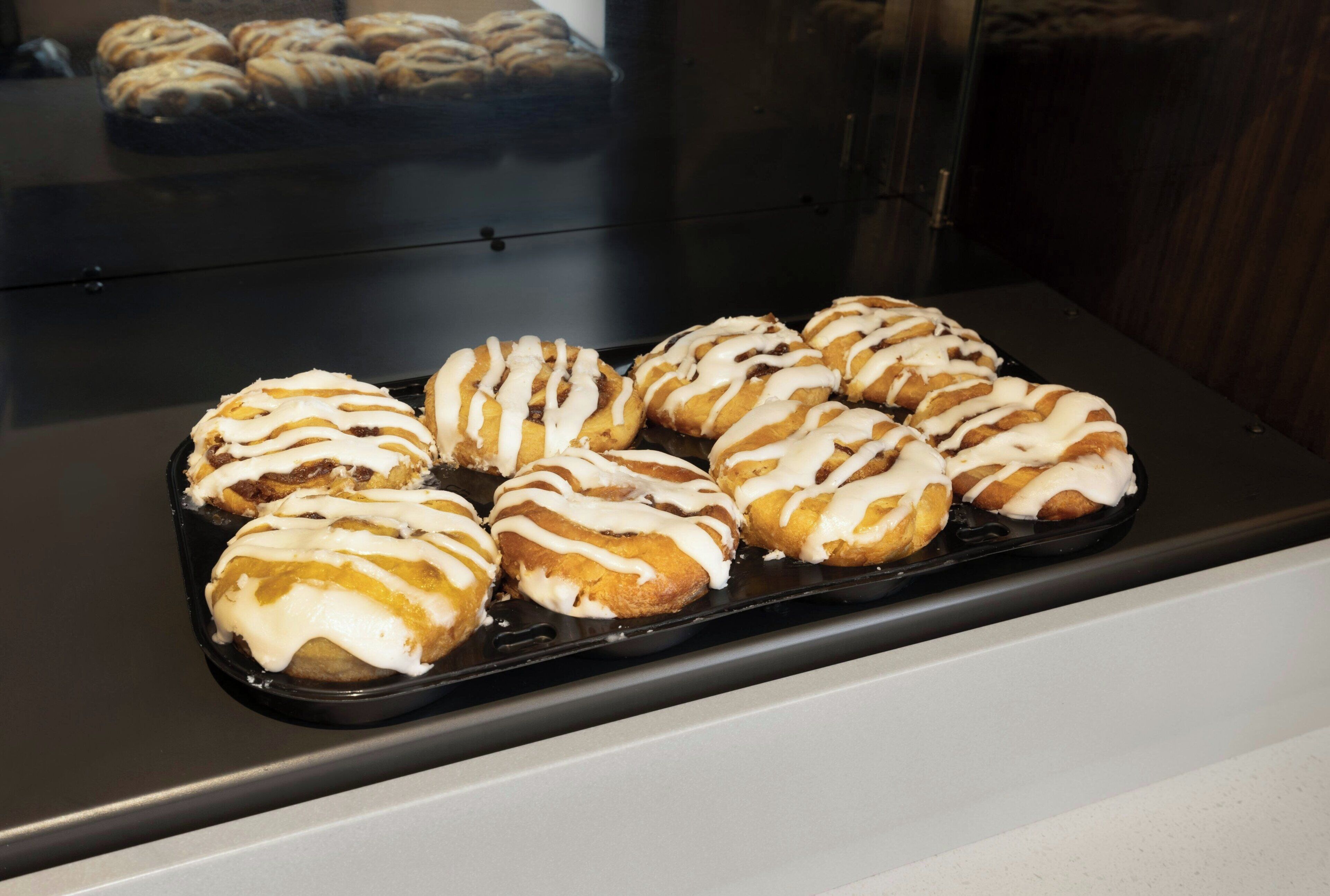 Une assiette de pâtisseries recouvertes d’un glaçage blanc, présentée sur un plateau noir.