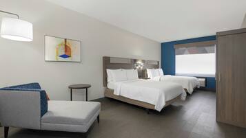 Habitación de hotel con cama, una silla, una mesita y un cuadro en la pared.