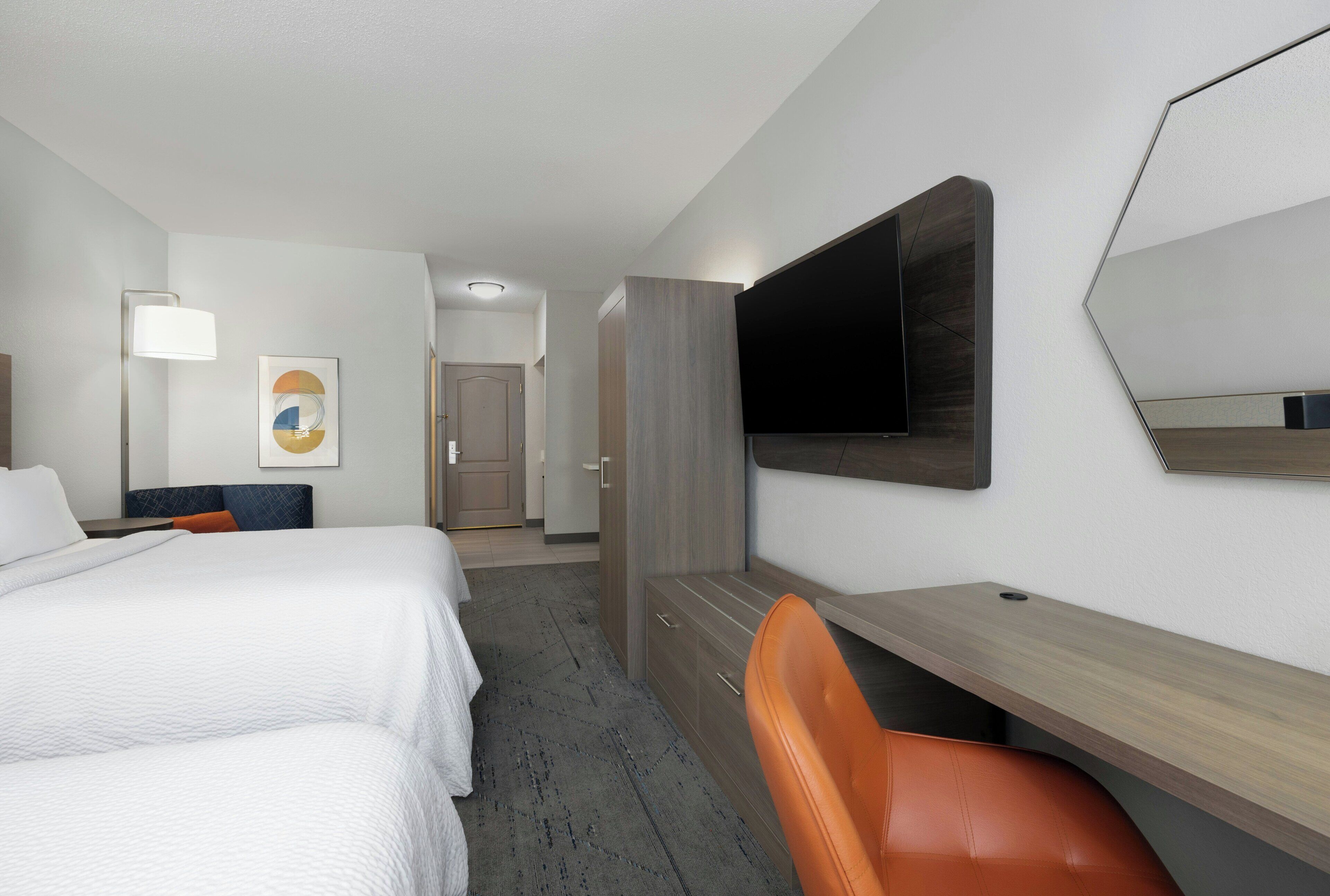 Een hotelkamer met een bed, een bureau, een stoel, een televisie en een deur naar een badkamer.