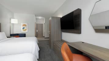Een hotelkamer met een bed, een bureau, een stoel, een televisie en een deur naar een badkamer.