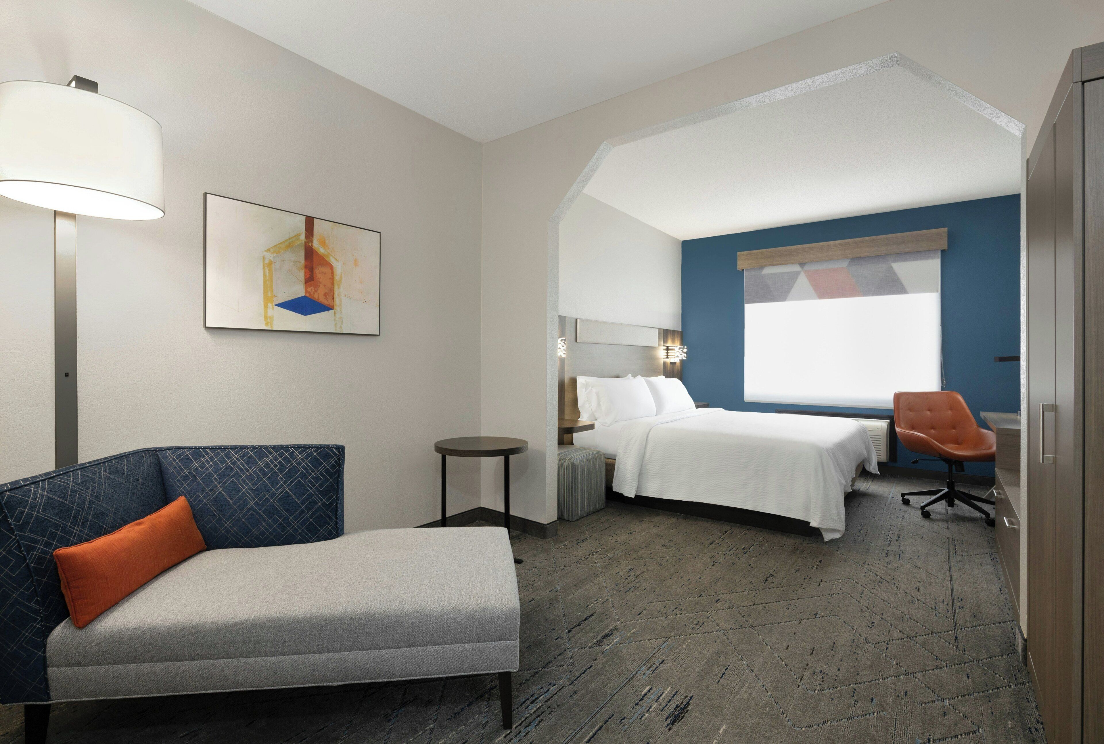 Une chambre d’hôtel avec un lit, une chaise, un bureau et une lampe.