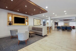A modern hotel lobby with a flat-screen TV, seating area, and a dining space. - Holiday Inn Express & Suites Acworth - Kennesaw Northwest by IHG (Acworth)