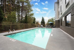 Una piscina al aire libre, sillones reclinables de piscina