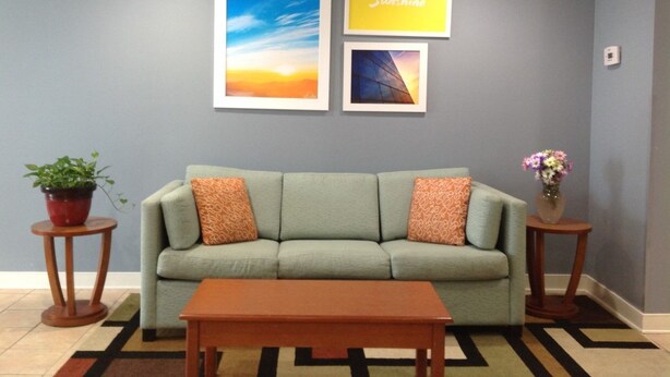 A living room with a sofa, two side tables, a coffee table, and framed pictures on the wall. - Days Inn by Wyndham Glen Allen/Richmond North (Glen Allen)