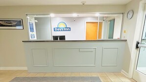 A reception desk with a Days Inn logo, a clock on the wall, and a tiled floor. - Days Inn by Wyndham Glen Allen/Richmond North (Glen Allen)