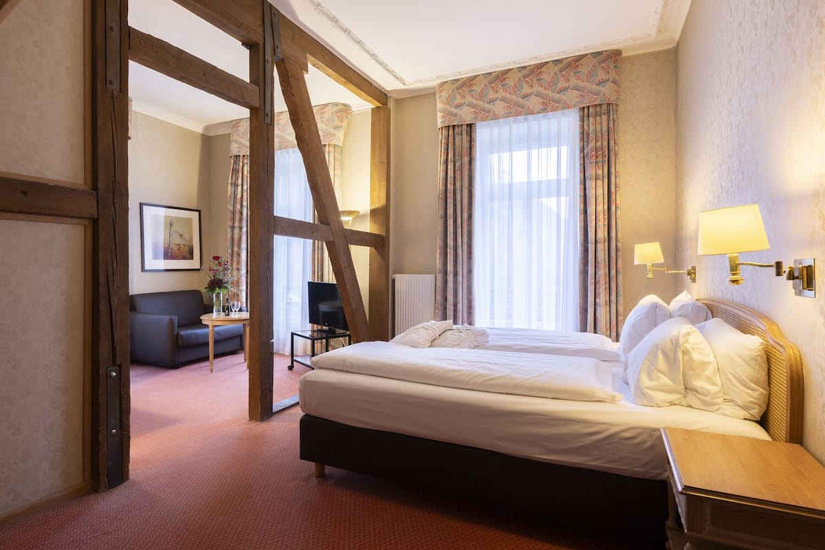 Ett hotellrum med en stor säng, ett skrivbord, en stol och en soffa.