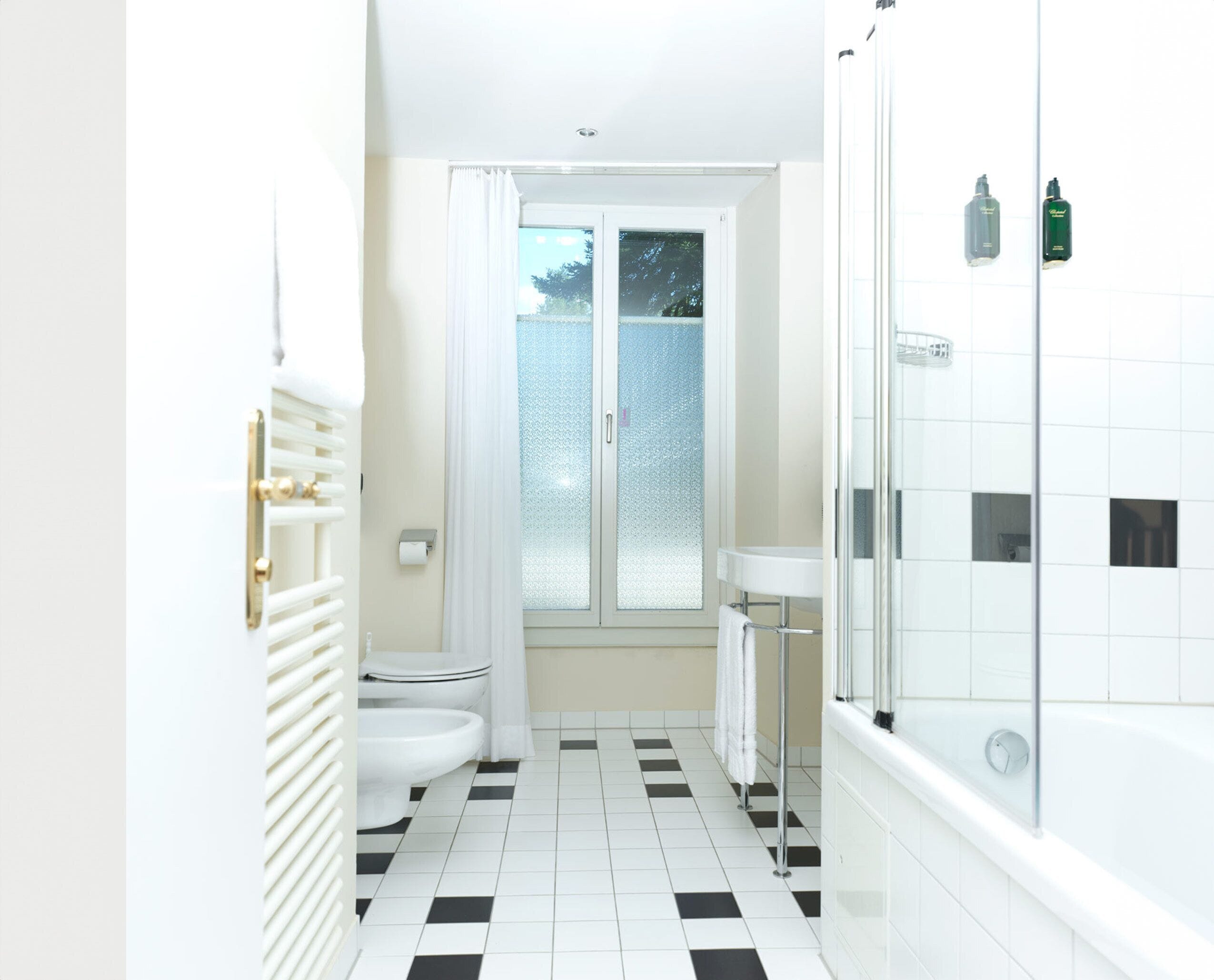 A bathroom with a black and white checkered floor, a toilet, a sink, and a shower.